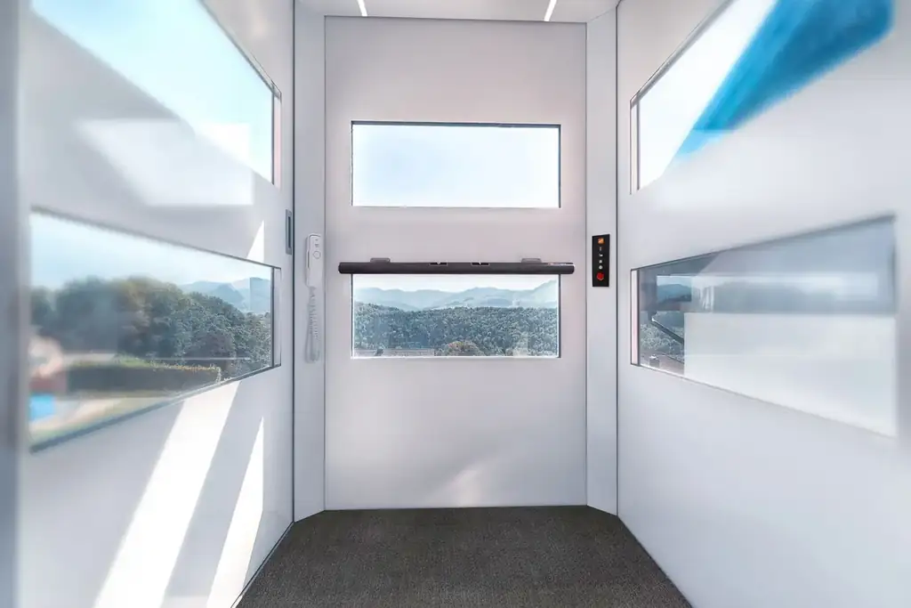 Blick in die Kabine mit Fenstern, Handlauf mit Bedienung und Notruftelefon